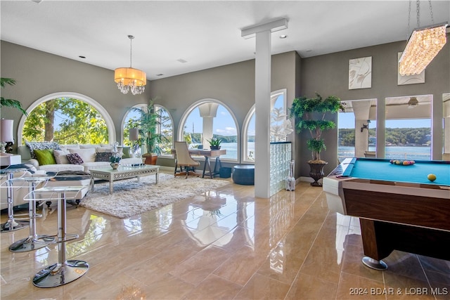 interior space with billiards, a chandelier, decorative columns, and a healthy amount of sunlight