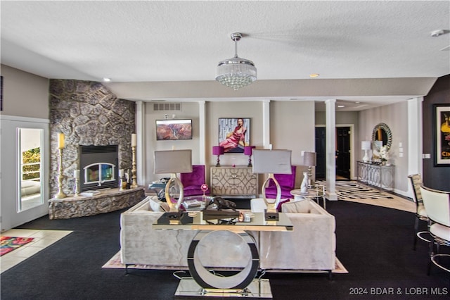 living room with carpet floors, decorative columns, a textured ceiling, and a stone fireplace