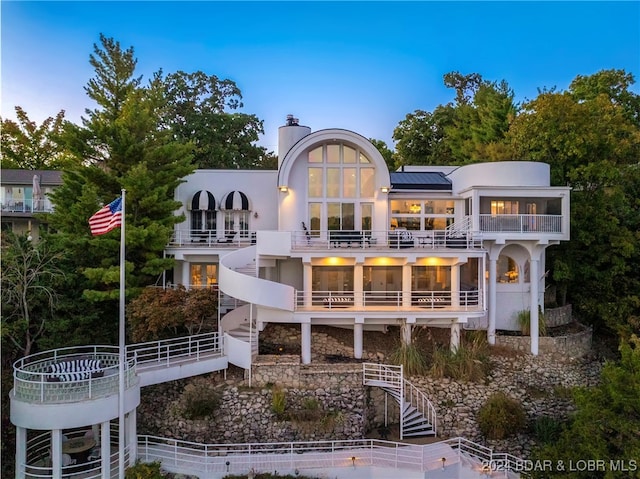 back house at dusk with a balcony