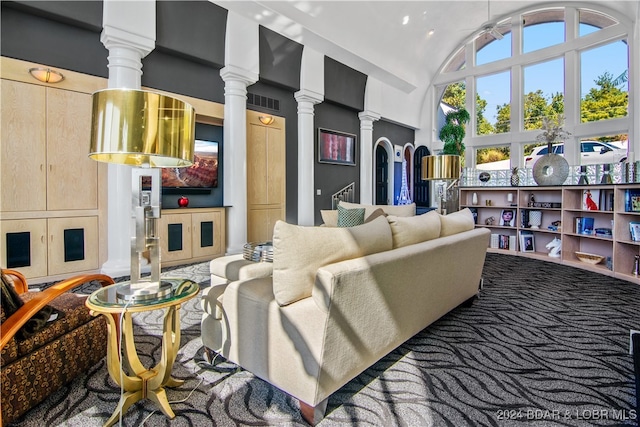 carpeted living room featuring ornate columns and lofted ceiling