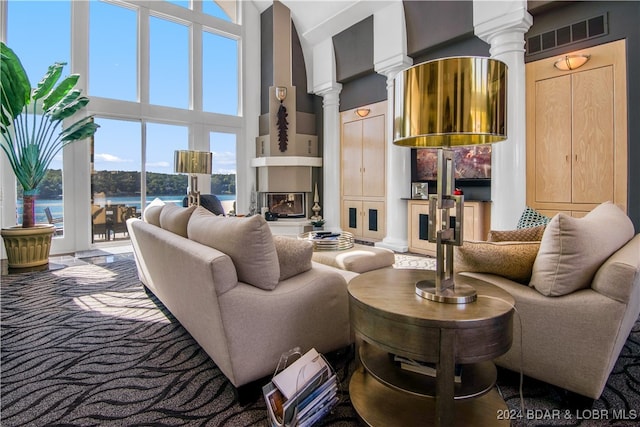 living room with a water view, a high ceiling, and decorative columns