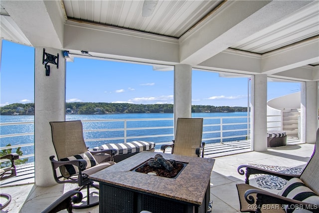 view of patio with an outdoor fire pit, a water view, and a balcony