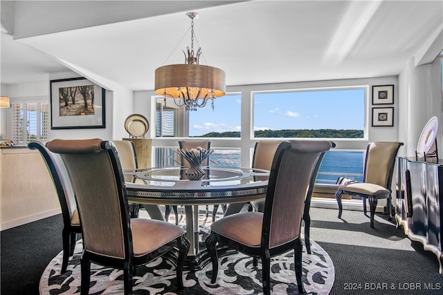 dining space featuring carpet floors, a chandelier, and a water view