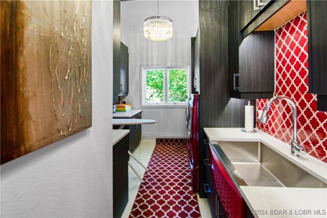 kitchen with pendant lighting, decorative backsplash, sink, and a chandelier