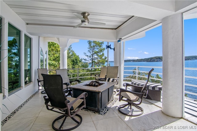 view of patio featuring a water view, ceiling fan, and a fire pit