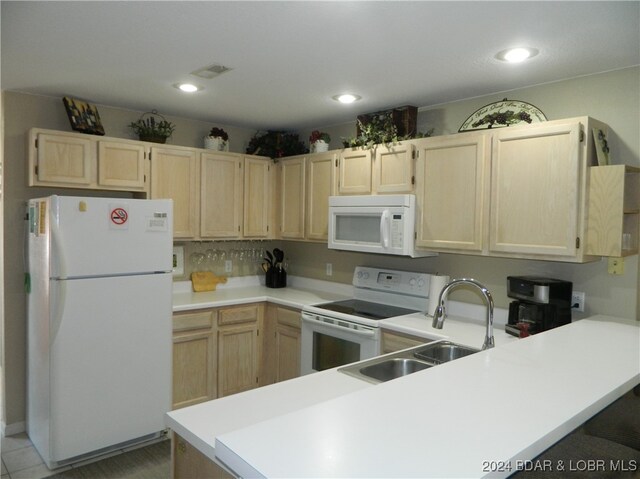 kitchen with light brown cabinetry, kitchen peninsula, sink, and white appliances