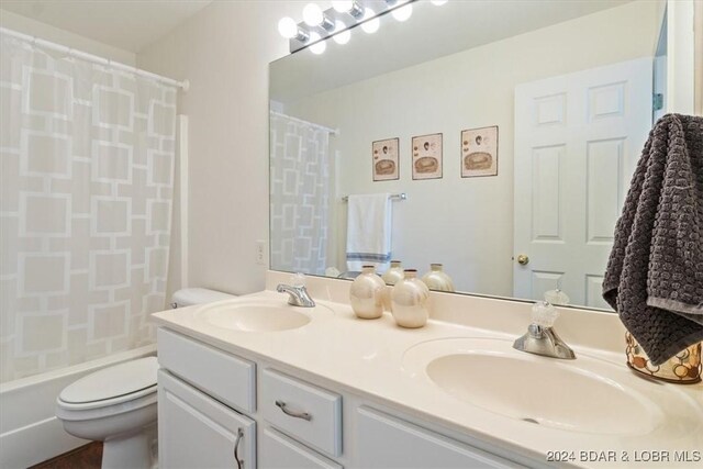 bathroom featuring a sink, shower / bathtub combination with curtain, toilet, and double vanity