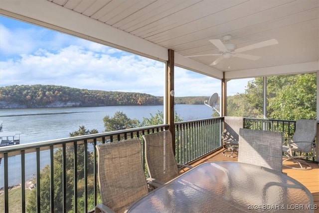 wooden deck featuring a ceiling fan, outdoor dining space, and a water view