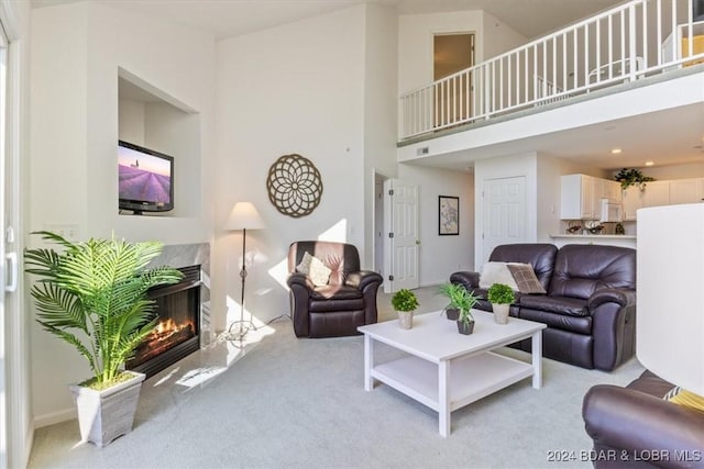 living room featuring light carpet, a premium fireplace, and a towering ceiling