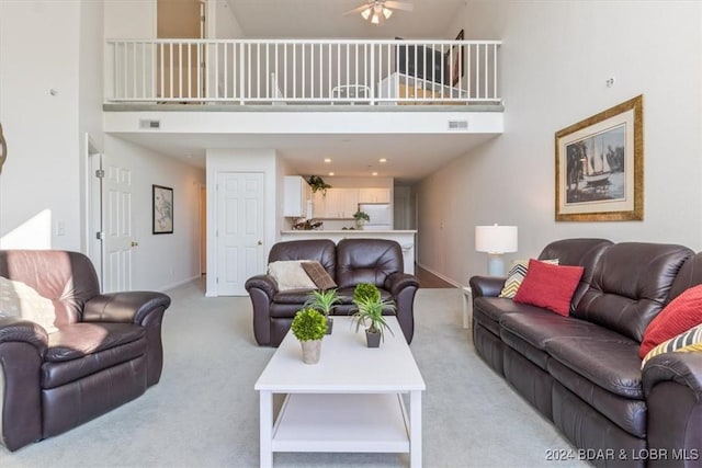 living room with a towering ceiling, baseboards, and light colored carpet