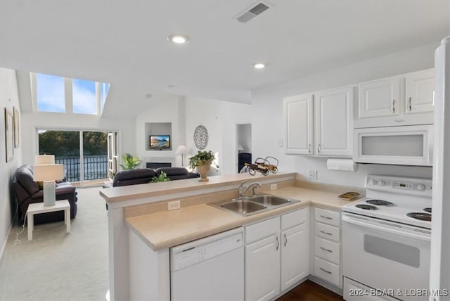 kitchen featuring open floor plan, a peninsula, white appliances, and a sink