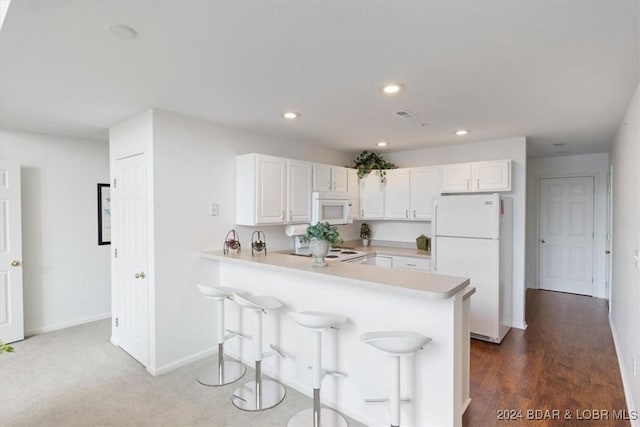 kitchen with light countertops, white appliances, a peninsula, and white cabinets