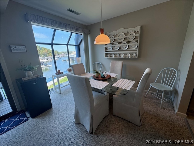 carpeted dining room featuring a water view