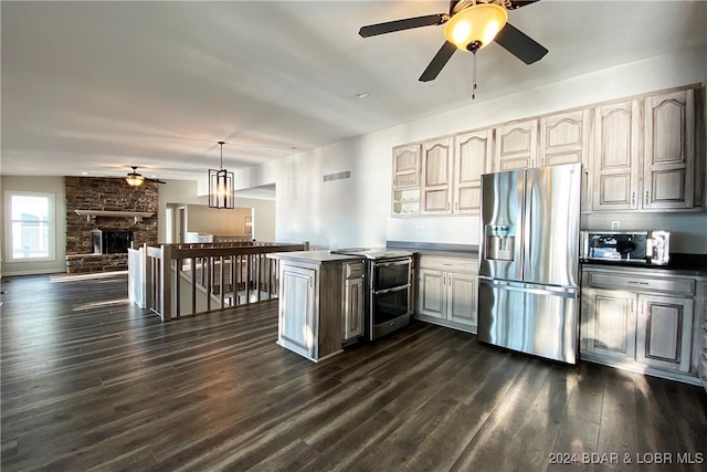 kitchen featuring stainless steel fridge, ceiling fan, dark hardwood / wood-style floors, a stone fireplace, and hanging light fixtures