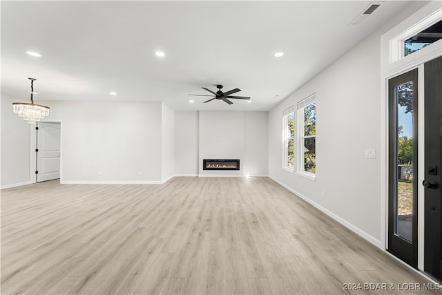 unfurnished living room with ceiling fan with notable chandelier and light hardwood / wood-style floors