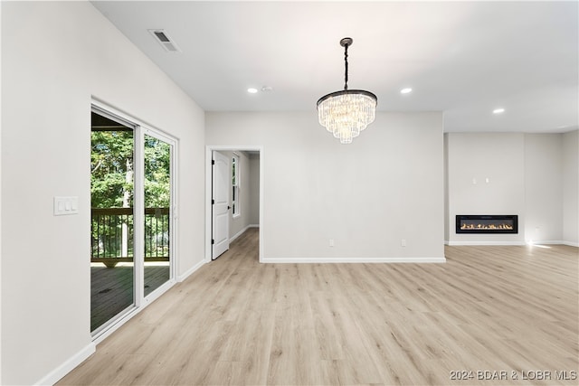 unfurnished living room with a chandelier and light hardwood / wood-style flooring