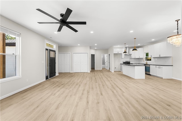 unfurnished living room featuring ceiling fan with notable chandelier, light hardwood / wood-style flooring, and sink