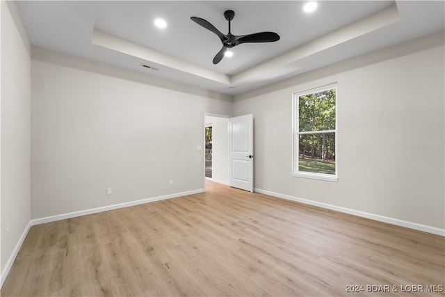 unfurnished room featuring ceiling fan, light hardwood / wood-style floors, and a raised ceiling