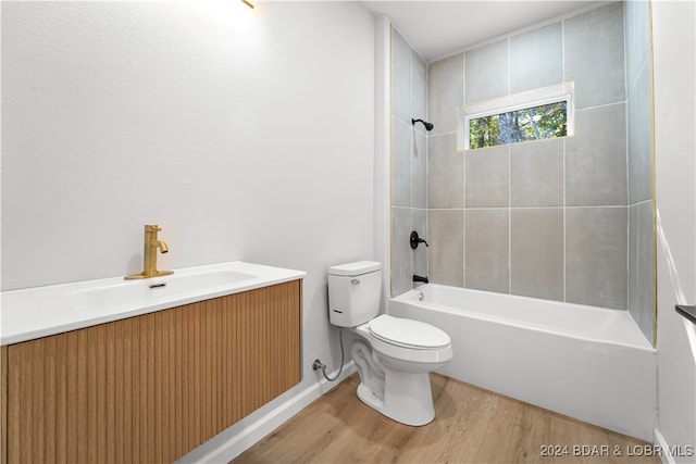 full bathroom with hardwood / wood-style floors, vanity, toilet, and tiled shower / bath