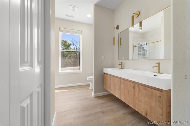 bathroom with hardwood / wood-style floors, vanity, toilet, and a shower