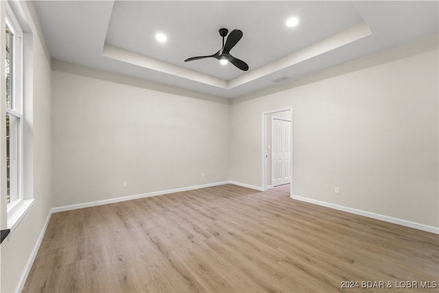 spare room featuring ceiling fan, light hardwood / wood-style flooring, and a raised ceiling