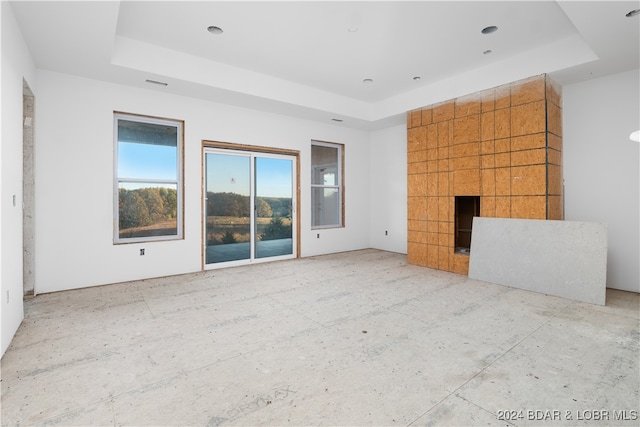 unfurnished living room featuring a raised ceiling and a large fireplace