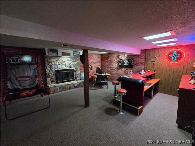 game room featuring a textured ceiling, a fireplace, wood walls, and carpet flooring