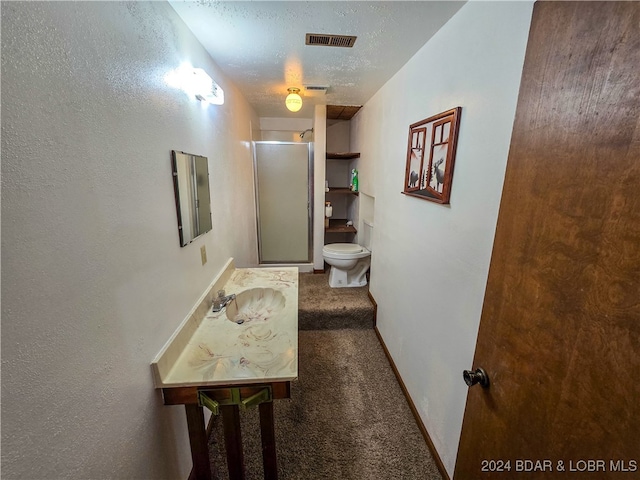 hallway with sink, dark carpet, and a textured ceiling