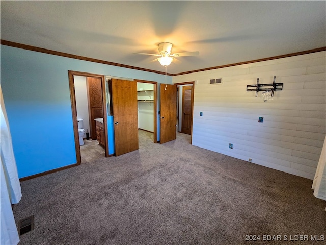 unfurnished bedroom with carpet floors, ornamental molding, ensuite bath, and ceiling fan