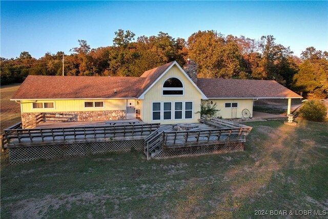 back of property featuring a wooden deck and a lawn