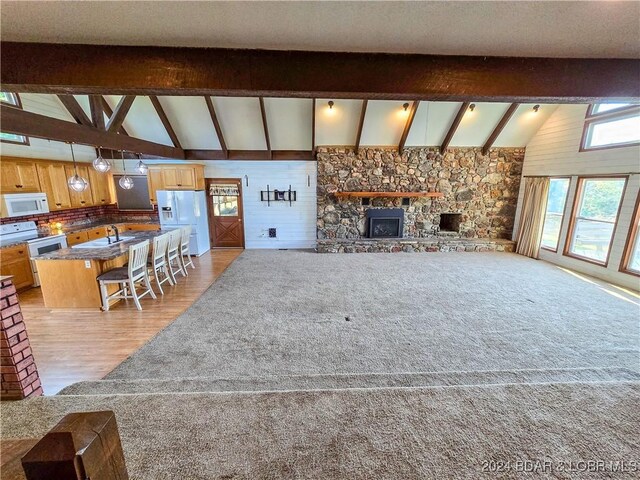 unfurnished living room with beamed ceiling, high vaulted ceiling, sink, and light wood-type flooring