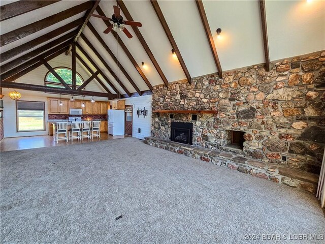 unfurnished living room with a fireplace, high vaulted ceiling, and beam ceiling