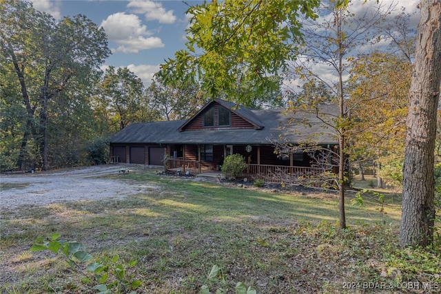 cabin with a garage, a porch, and a front lawn