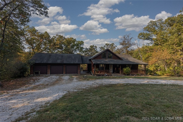 view of front of property featuring a front lawn, covered porch, and a garage