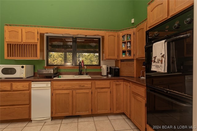 kitchen featuring light tile patterned flooring, black double oven, and sink