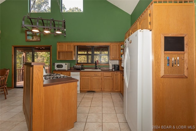 kitchen with high vaulted ceiling, white appliances, and light tile patterned floors