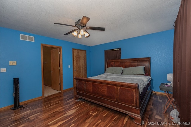 bedroom with ceiling fan, a textured ceiling, and dark wood-type flooring