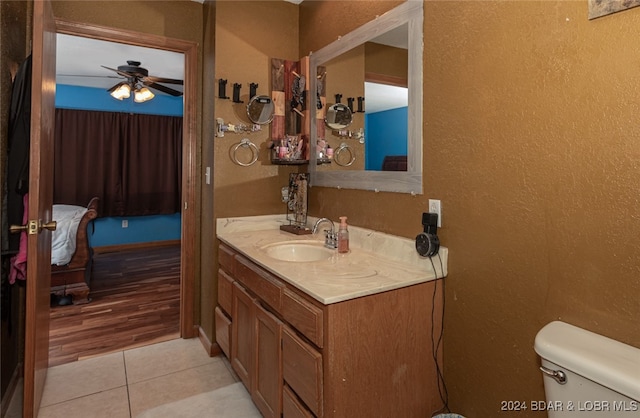 bathroom with wood-type flooring, ceiling fan, vanity, and toilet