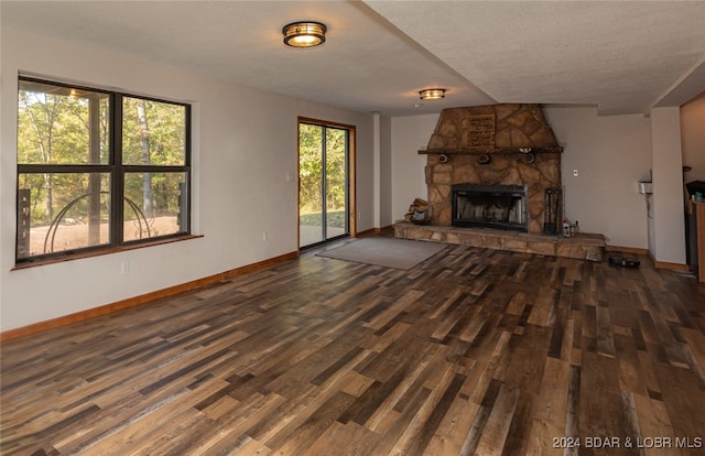 unfurnished living room with hardwood / wood-style floors, a textured ceiling, and a stone fireplace