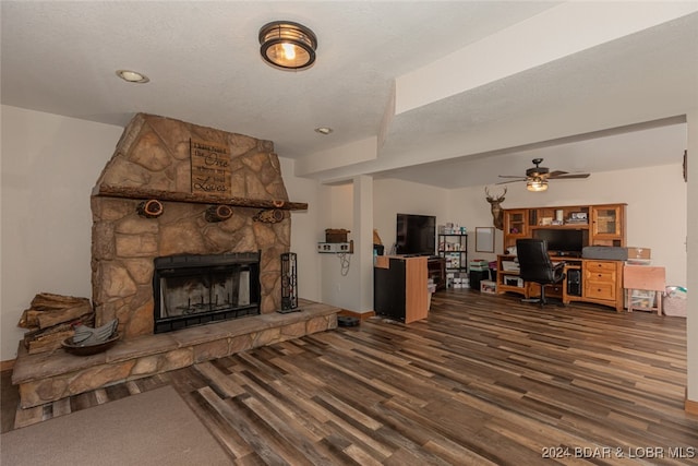 living room featuring a fireplace, ceiling fan, dark hardwood / wood-style floors, and a textured ceiling