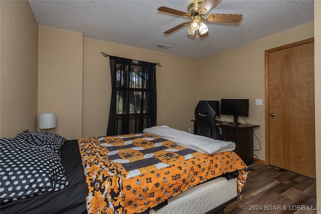 bedroom featuring ceiling fan, dark wood-type flooring, and a textured ceiling