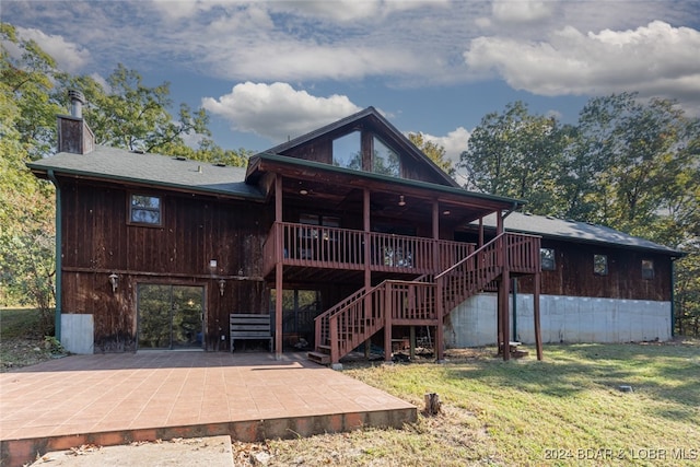 rear view of house with a wooden deck, a lawn, and a patio area