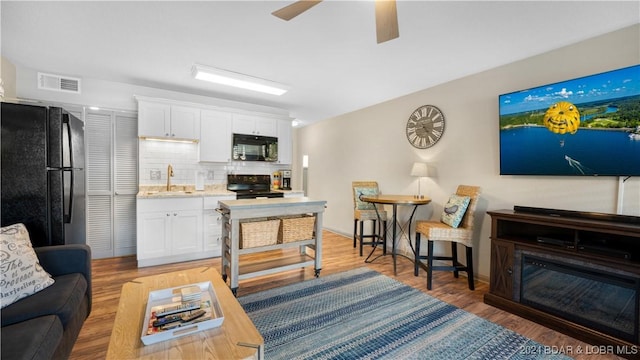 living room with hardwood / wood-style flooring, ceiling fan, and sink