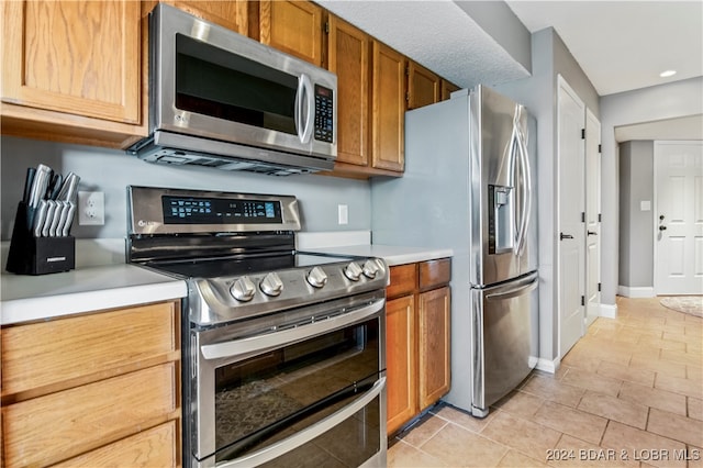 kitchen with light tile patterned floors and stainless steel appliances