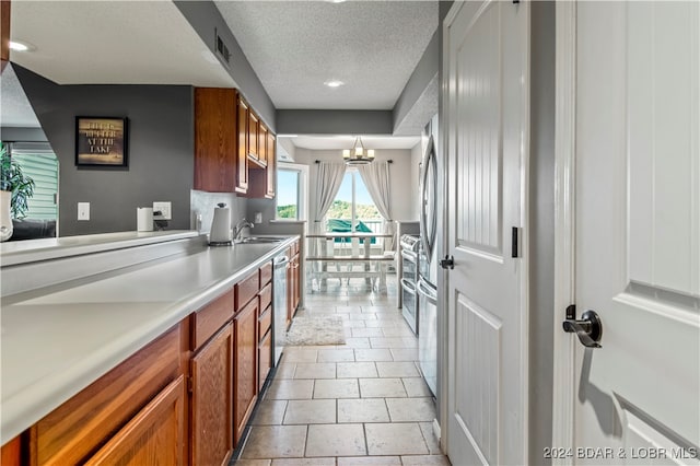 kitchen with dishwasher, sink, hanging light fixtures, an inviting chandelier, and a textured ceiling