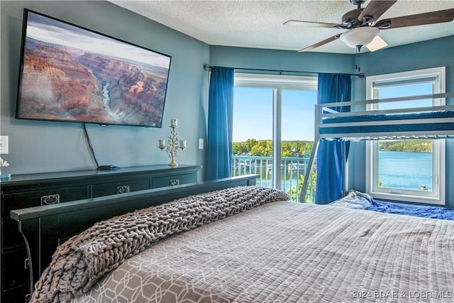 bedroom featuring a water view, access to outside, a textured ceiling, and ceiling fan