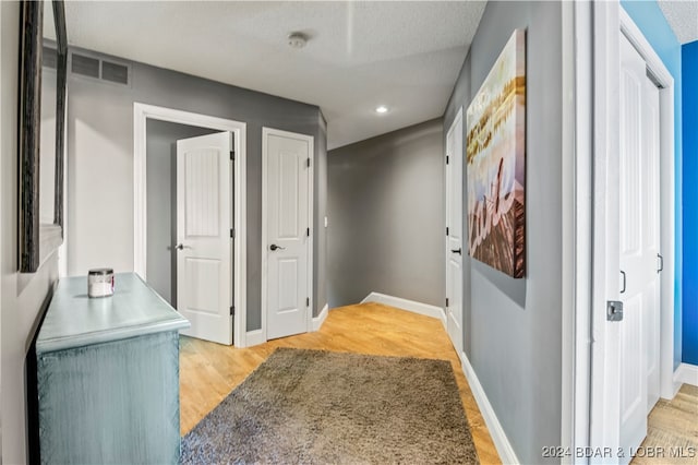 hall featuring a textured ceiling and light hardwood / wood-style floors