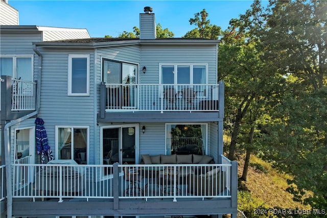 rear view of property featuring an outdoor living space and a balcony