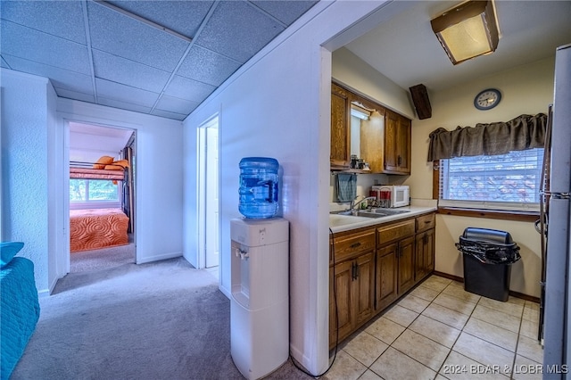 kitchen featuring a drop ceiling, fridge, sink, and light carpet