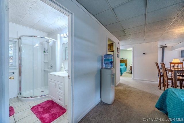 bathroom with a drop ceiling, tile patterned floors, vanity, and walk in shower